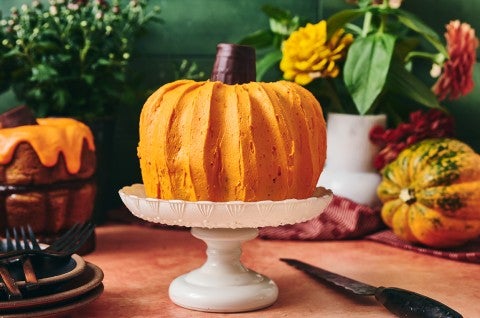 A bundt cake shown atop a white pedestal that looks very much like a pumpkin. - select to zoom