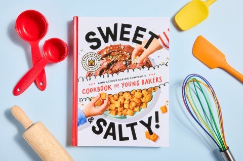 Cookbook with baking tools scattered around. 