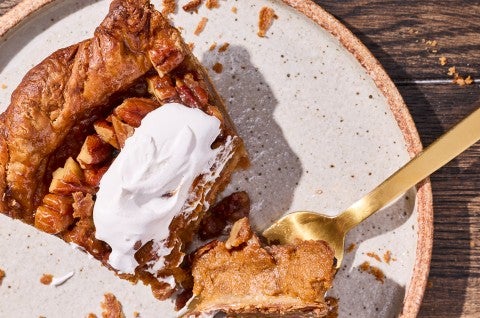 Detailed photograph of a bite of pumpkin pecan pie topped with whipped cream on top of a fork. - select to zoom