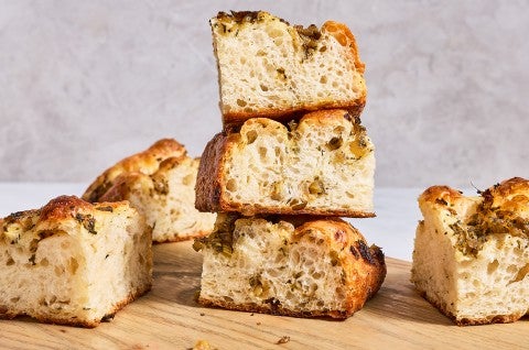 Focaccia chunks stacked and placed on a cutting board. - select to zoom