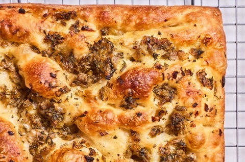 Detail of the corner of a stuffing focaccia showing integrated ingredients and browning of the bake. - select to zoom