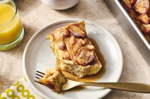 A slice of Apple French Toast Bake on a light colored plate with a bit atop a fork. - select to zoom