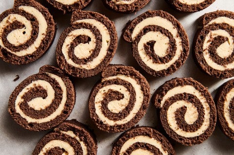 Sliced pinwheels of chocolate cake filled with Cookie Butter Whipped Ganache all laying side by side on a sheet tray. - select to zoom