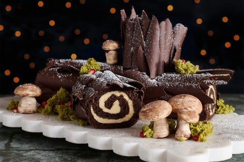 Chocolate Buche de Noel with Cookie Butter Whipped Ganache seen from the side with edible woodland decorations. - select to zoom