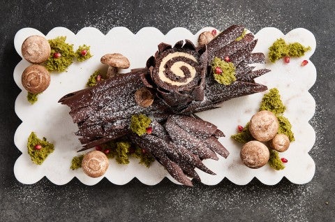 Chocolate Buche de Noel with Cookie Butter Whipped Ganache showing beautiful layers of chocolate coated cake and edible decorations in the style of a log. - select to zoom