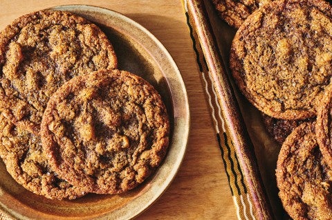Overhead view of Cape Cod Soft Molasses Cookies shown on a plate and also on a baking sheet. - select to zoom