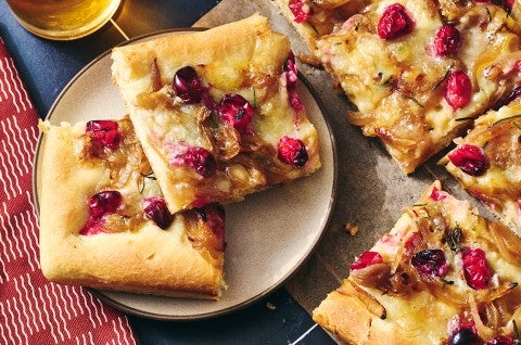 Slices of Caramelized Onion and Brie Pizza on a plate showing a golden baked top dotted with pomegranate, brie, and caramelized onion. - select to zoom