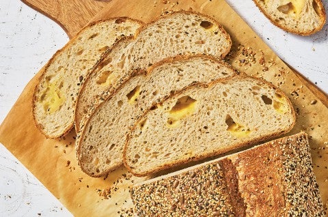 Parmesan Black Pepper Sourdough Bread sliced and laid out on a wooden cutting board showing an airy bread with cheese in the air pockets. - select to zoom