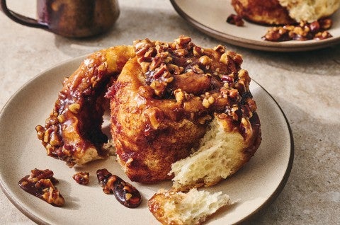 Photograph of a dark brown sticky bun peeled apart showing with a sweet and perfectly baked interior. - select to zoom