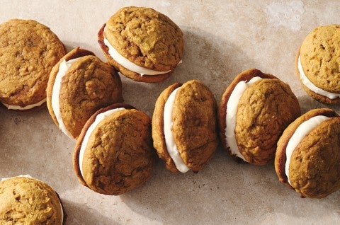 Pumpkin Whoopie Pies photographed together on a counter showing the layers of pumpkin cookie and creamy filling. - select to zoom