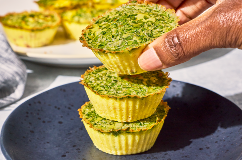 Egg Bites stacked on a plate with a hand picking one up off the top. - select to zoom