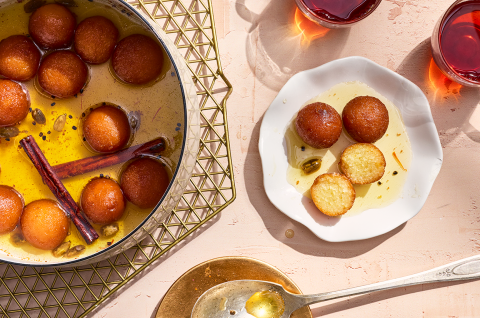Gulab Jamun in a bowl with the fragrant syrup and some on a plate. - select to zoom