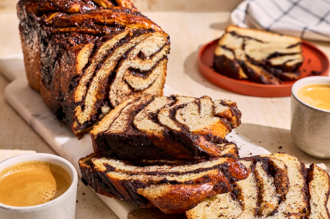 Chocolate Sourdough Babka sliced and arranged on a table with coffee and other plates. - select to zoom
