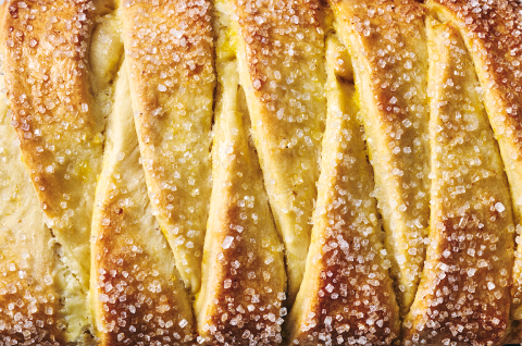 Detailed photo of Cheese Filled Sweet Braid seen from above showing sparkling sugar and a overlapping layers of bread. - select to zoom