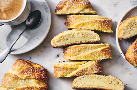Cheese Filled Sweet Braid sliced on a counter with a cup of coffee in the corner. - select to zoom