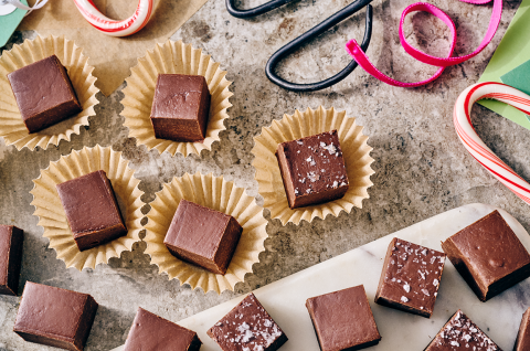 Easy Microwave Fudge cut into neat squares and placed in small paper cups with scissors and ribbon in the shot. - select to zoom