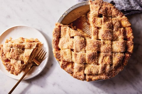 An apple pie in a pie tin and a slice on a plate. - select to zoom