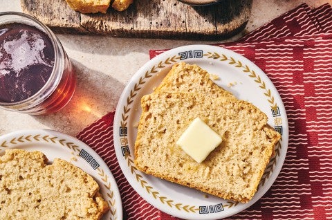 Sliced classic beer bread on a table with butter and a cutting board. - select to zoom