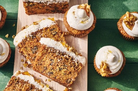 Spiced Carrot Snacking Cake on a cutting board with cupcakes around it. - select to zoom