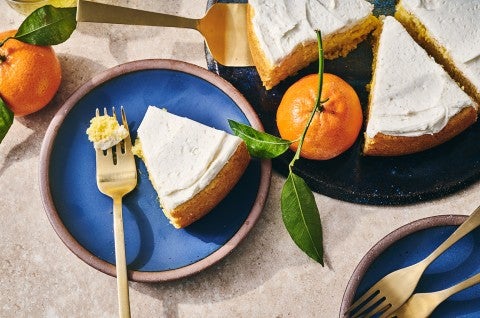 A slice of whole orange cake ona. blue plate with a bite on a fork. - select to zoom