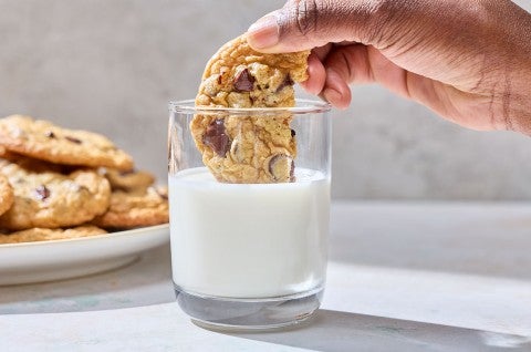 Dipping a Cream Cheese Chocolate Chip Cookie into a glass of milk. - select to zoom