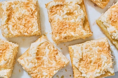 Creamy Coconut Sheet Cake shown sliced and arranged on a counter. - select to zoom