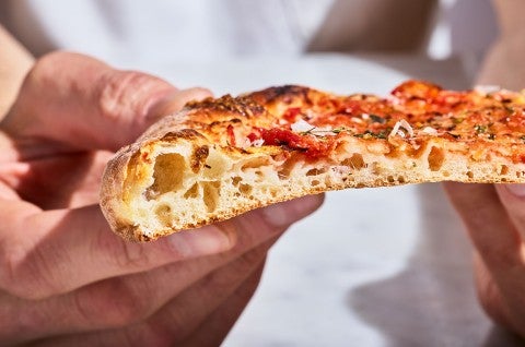 A slice of New York-Style Pizza showing the thin and airy dough from the side. - select to zoom