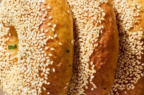 Close of up three Sesame Sourdough Discard Bagels on an angle showing the sesame seeds and dark bake. - select to zoom