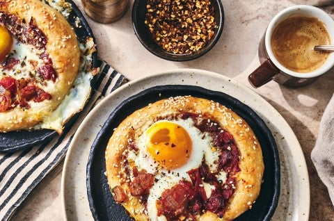 Breakfast Shakshuka shown on a plate with coffee and hot pepper flakes also in the picture. - select to zoom