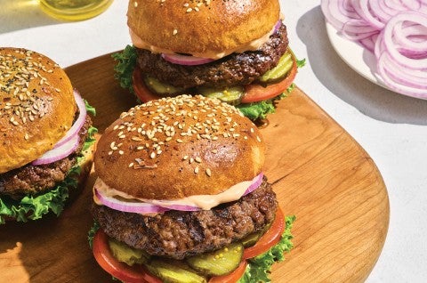 Hamburgers in Whole Wheat Hamburger Buns on a cutting board. - select to zoom