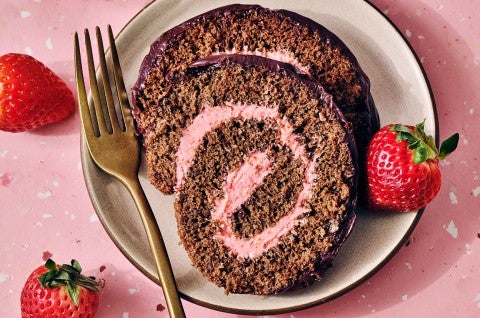 Chocolate Strawberry Roll Cake on a plate with a pink strawberry swirl clearly depicted in the cake. - select to zoom