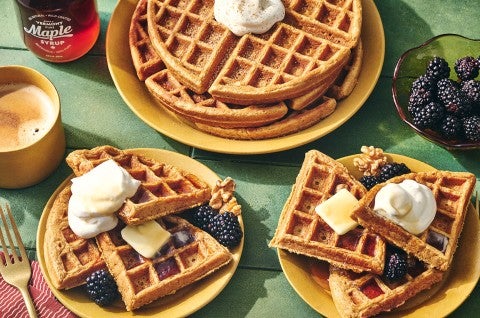 Gingerbread Waffles on a green countertop with some on plates and others stacked. - select to zoom