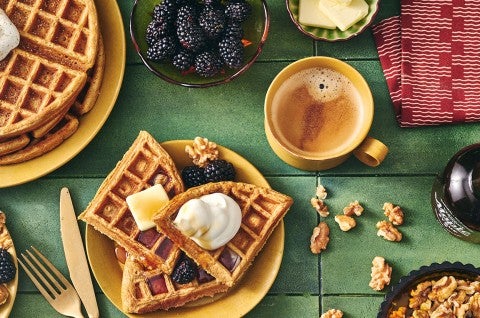 Gingerbread Waffles on a plate with whipped cream, butter, syrup, and fresh berries. - select to zoom