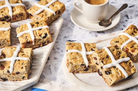 Gluten Free Hot Cross Biscuits on a table with a coffee in the background. - select to zoom