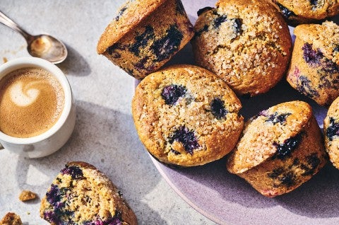 Sourdough Discard Blueberry Muffins on a counter with a cup of coffee in the frame. - select to zoom