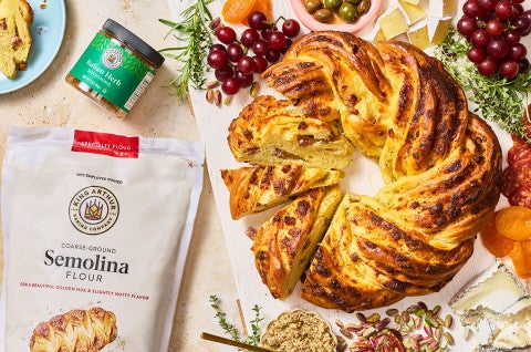 An Italian Herb & Cheese Wreath seen from above with a bag of semolina flour and italian herb blend from King Athur Baking - select to zoom