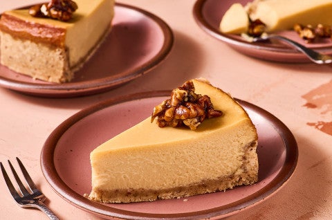 A slice of Maple Pecan Cheesecake on a pink plate, seen from the side - select to zoom