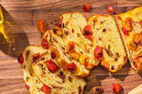 No-Knead Cheese and Tomato Garlic Bread sliced and shown on a wooden counter - select to zoom