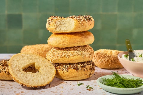 Various bagels stacked on a counter. - select to zoom