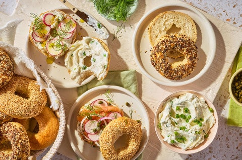 An arrangement of bagels on a counter with various spreads and toppings. - select to zoom
