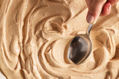 Swirling Brown Butter Cream Cheese Frosting with a spoon - select to zoom