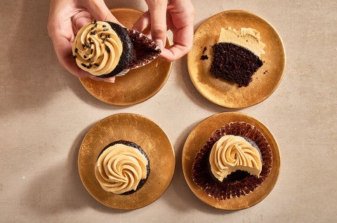 Peeling a cupcake wrapper from a Chocolate Cupcake with Whipped Caramel Frosting - select to zoom
