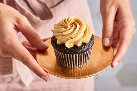 Holding a plate with a Chocolate Cupcake with Whipped Caramel Frosting on it - select to zoom