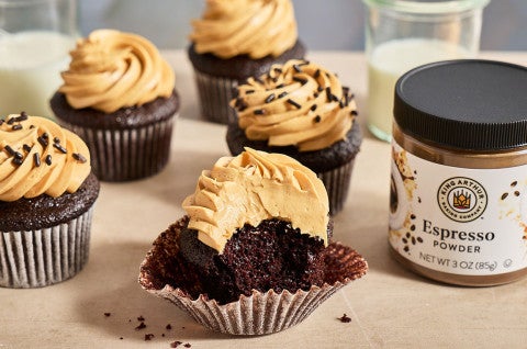 Chocolate Cupcakes with Whipped Caramel Frosting seen from the side with a jar of espresso powder from King Arthur Baking - select to zoom