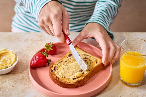 Spreading butter on a slice of Sourdough Cinnamon Swirl Bread - select to zoom