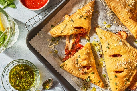 Flaky Puff Crust Pizza Turnovers on a baking sheet with herbs seen from above - select to zoom
