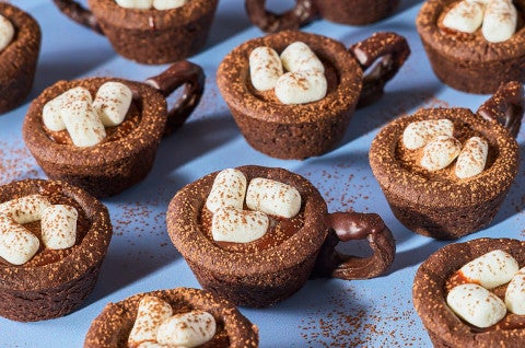 Hot Cocoa Cookie Cups arranged on a blue countertop. - select to zoom