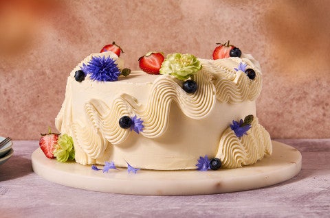 A cake frosted with Italian Buttercream and adorned with flowers, fruits and berries - select to zoom