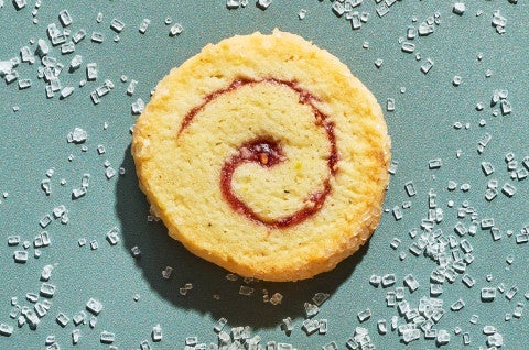 An Any-Jam Pinwheel Cookie on a counter surrounded by sparkling sugar - select to zoom
