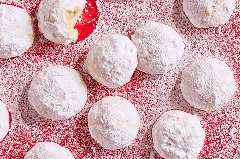 Lemon Snowball Cookies coated in powdered sugar on a red surface - select to zoom